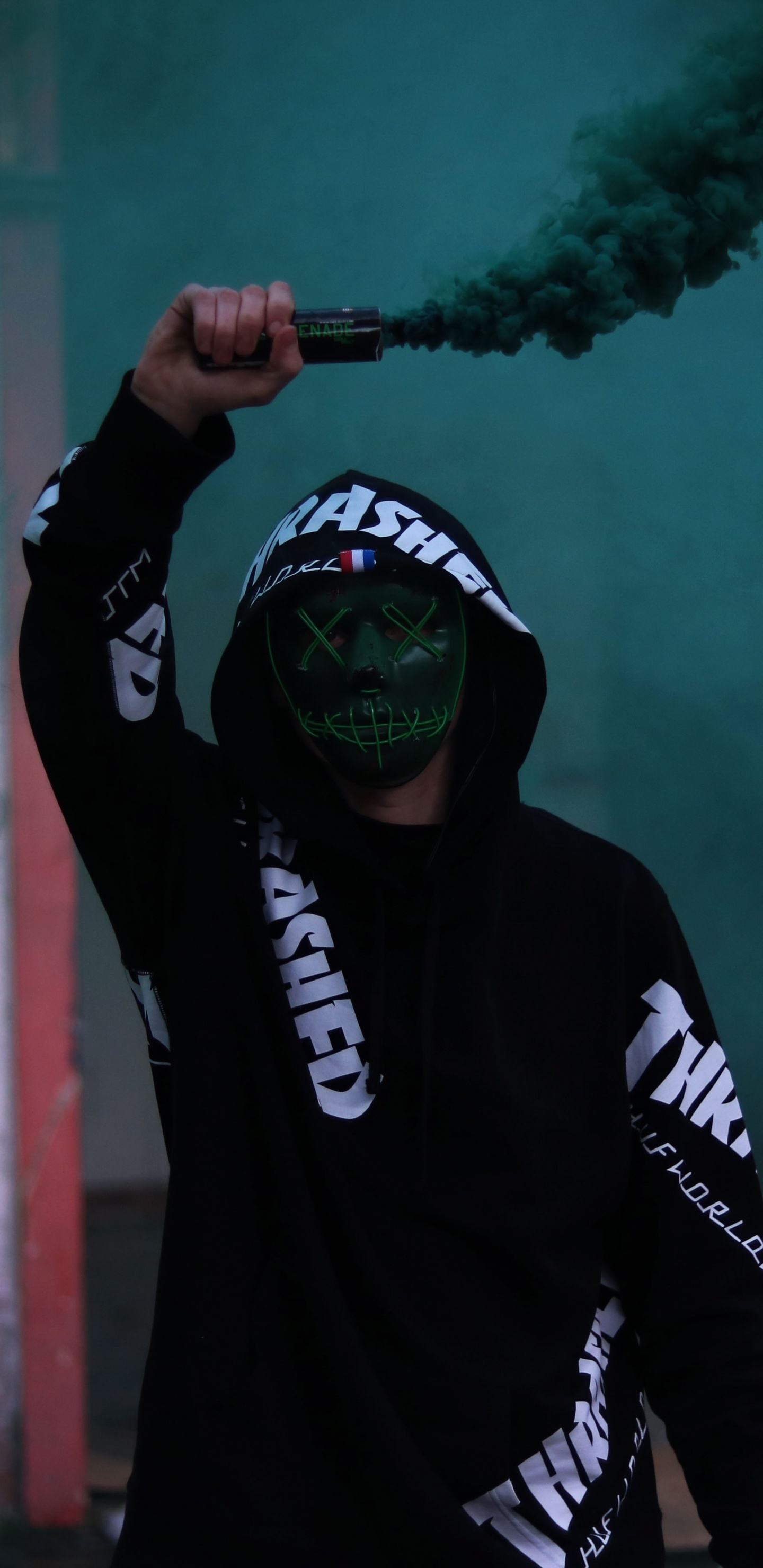 Обои мужчина держит дым, дымовая граната, цветной дым, темнота, шапка в разрешении 1440x2960